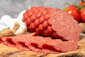 Sausage and slices on cutting board. Cold sausage slices on gray background. Close up