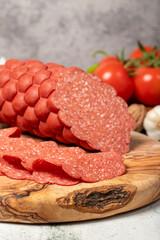 Sausage and slices on cutting board. Cold sausage slices on gray background. Close up