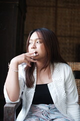 a beautiful Asian woman is enjoying the cigarette she is holding