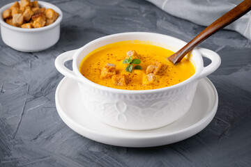 Pumpkin soup with croutons on grey background