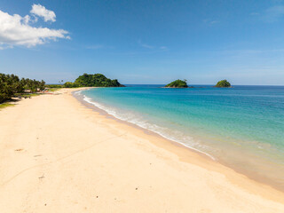 Ocean waves crashing over cream colored sands in Nacpan Beach. El Nido, Philippines.