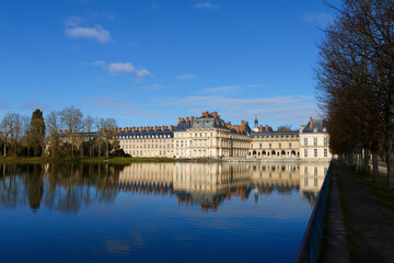 Beautiful Medieval landmark - royal hunting castle Fontainbleau with reflection in water of pond. - 743147587