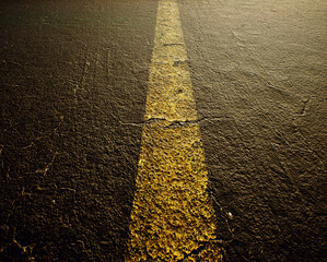 Worn out and cracked old asphalt of a highway with a yellow divide line. Detail shot. - 743154766