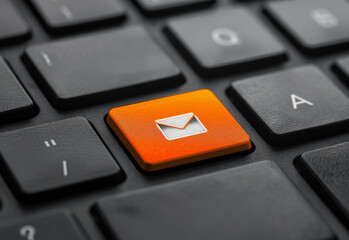 Close-up of a keyboard with an orange email icon key. Email marketing or newsletter concept