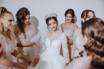 Bridesmaids rejoice in the morning, helping to fasten the buttons on the wedding dress and prepare...