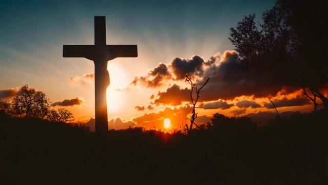 Silhouette of cross of Jesus Christ with trees on backlight at sunset. Dramatic sunrise sky lighting up a silhouetted christian cross in a Easter background.