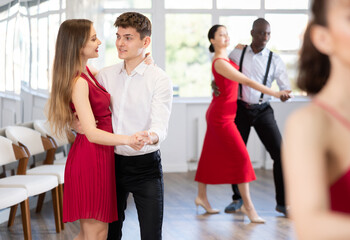 With unhurried music, guy and young woman in couple spins to rhythm of waltz during lesson for...