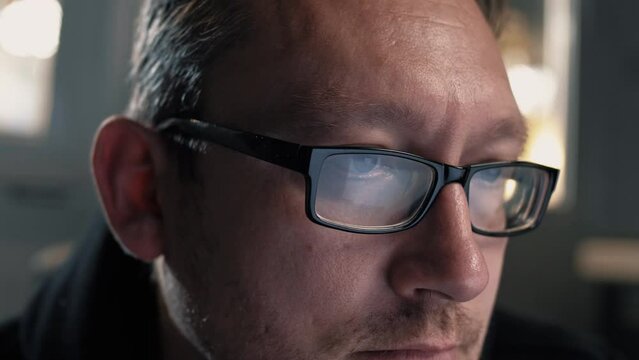 Portrait of a man wearing glasses in the light from the monitor screen. Close-up