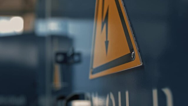 Installation of a high voltage warning sign at the entrance of an electrical substation using a pneumatic riveter 
