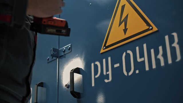 Attachment of a yellow triangle with a lightning bolt to warn of the dangers of high voltage. Close-up 