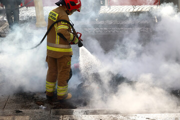 Strażak w kłębach dymu gasi pożar. - obrazy, fototapety, plakaty