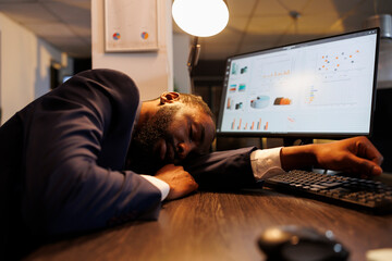 Exhausted tired businessman suffering from sleepiness after working overtime at project in startup...