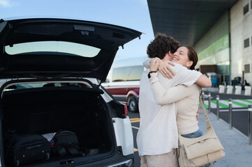 Emotional goodbye at the airport with open trunk