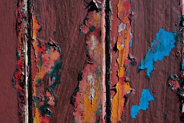 Macro shot of a weathered wooden surface with layers of chipped paint in various colors