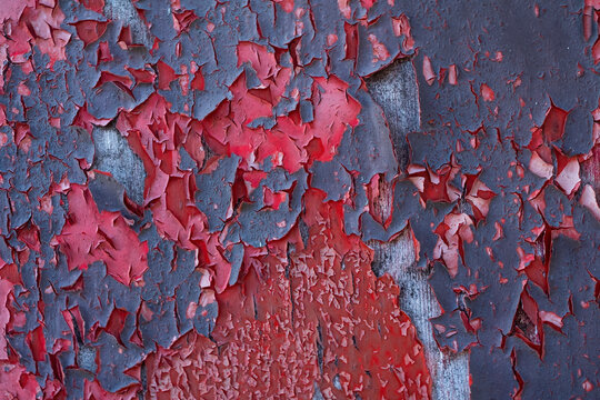 Macro photograph showcasing the detailed texture of cracked and peeling red paint on a metal surface