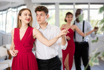 Energy man and young woman are dancing classic version of waltz in couple during lesson at studio....