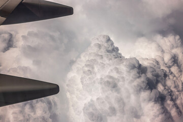 Fototapeta premium Aerial scene of cloudy sky viewed from airplane window during flight with continuous blanket of clouds.