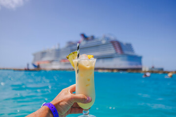 Beautiful view of man's hand holding glass of alcoholic cocktail with cruise liner in the...