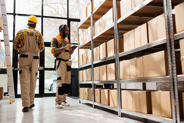 African american warehouse employee in headphones overseeing parcels security and maintenance. Post...