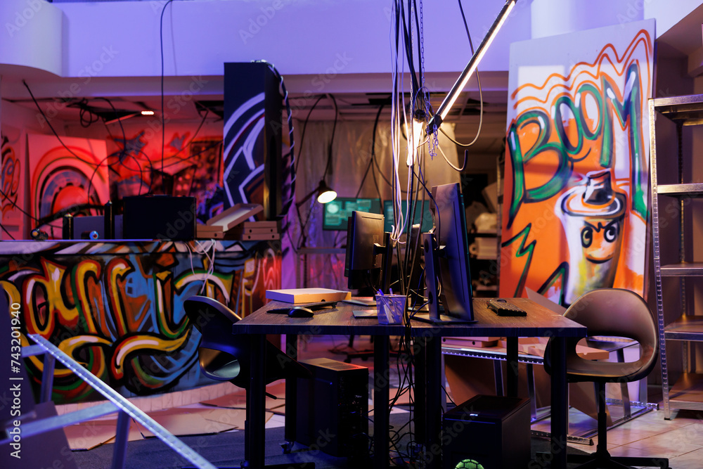 Poster internet criminals abandoned warehouse with graffiti at night time. computers on desks and equipment