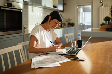 Woman doing bills with laptop at home