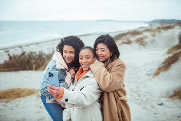Three friends taking a selfie on the beach in winter