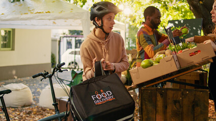 Small business owner giving food order to delivery woman, working on delivering organic fresh...