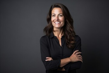 Portrait of a smiling businesswoman with arms crossed over dark background