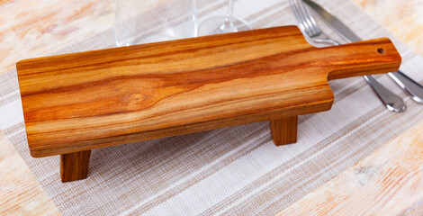 Closeup of empty natural wooden board for serving variety of breakfast items. Kitchen utensils for...
