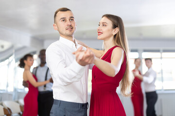 Adult man and young woman dance ballroom dance waltz in studio