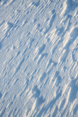 Beautiful winter background with snowy ground. Natural snow texture. Wind sculpted patterns on snow surface.