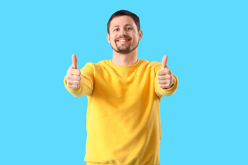 Handsome man showing thumbs-up on blue background