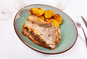 Roasted meaty pork ribs served on plate with fried golden baked potatoes.
