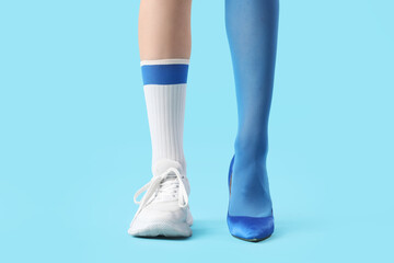 Legs of young woman in different stylish shoes on blue background
