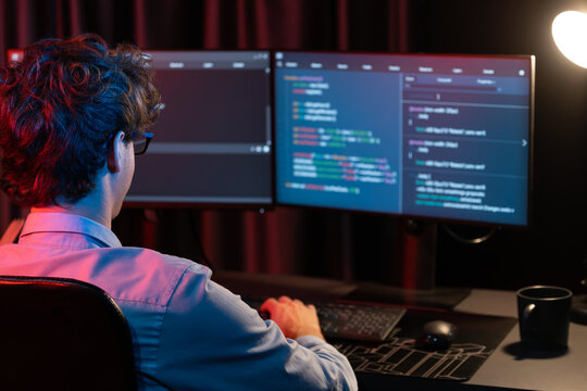 Working IT developer concentrating online software development information on surrounded by coding application pc screens, creating program for firmware on website at neon modern office home. Gusher.