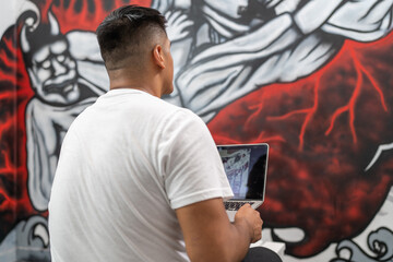 Street painter using a laptop to work on a mural
