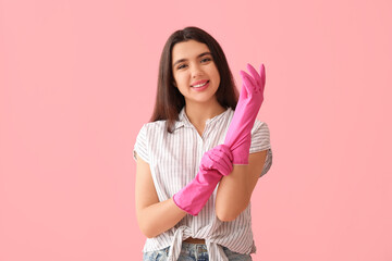 Young woman with rubber gloves on pink background