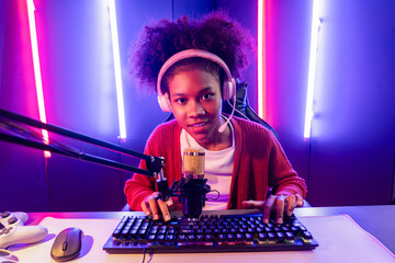 Host channel of gaming streamer, African girl taking, typing with Esport skilled team player and viewers online game in neon color lighting room. Concept of cybersport indoor activities. Tastemaker.