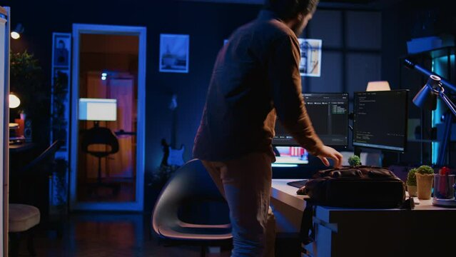 Freelancing software programmer arriving in personal office at home, resuming work on coding. Self employed IT specialist starting job shift in apartment, writing lines of code on computer, camera B