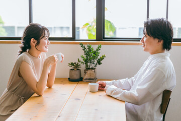 カフェ・家のダイニングで会話する仲良しの若い日本人夫婦
