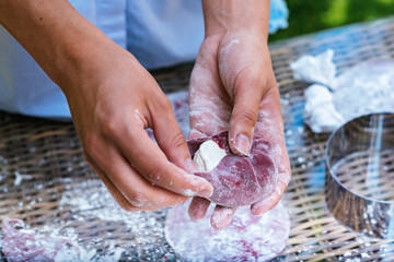 A person is holding a piece of dough in their hands, a common gesture in cooking. The soft texture...