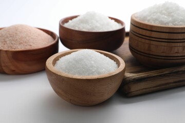 Fototapeta na wymiar Different types of natural salt in wooden bowls on white background