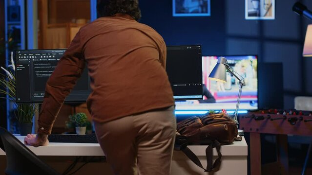 Remote software developer arriving in personal office at home, resuming work on javascript programming. IT engineer starting job shift in apartment, writing lines of code on computer