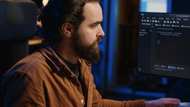 Focused programmer drinking coffee in apartment while solving database errors on computer. Remotely working IT admin concentrated on finalizing coding project in home office, camera A