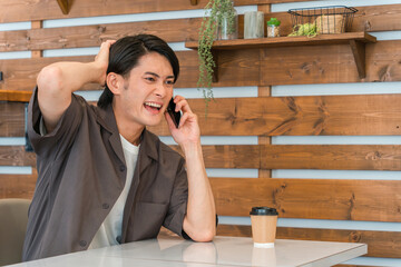カフェで電話する若いアジア人男性（うっかりミス・ヒューマンエラー）
