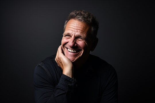 Portrait of a happy senior man laughing against a dark background.
