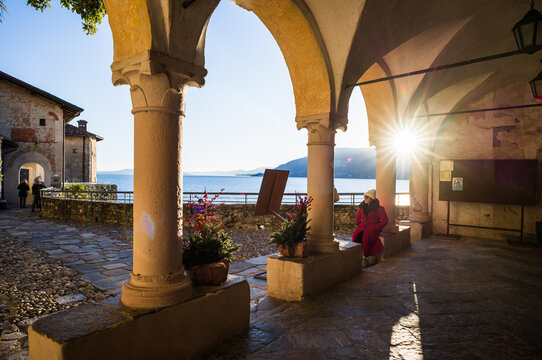 Asian woman sitting in the cloister of a monastery, Lake Maggiore, Santa Caterina del Sasso, Lombardy, Italy