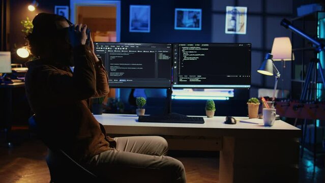 Teleworking programmer using futuristic VR glasses in home office to do javascript programming. IT expert wearing high tech virtual reality headset to visualize lines of code, camera B