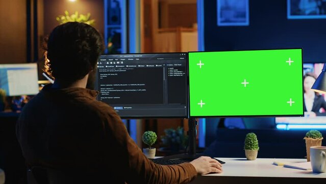 Self employed man doing IT support job from apartment personal office, coding on green screen PC. Software developer writing lines of code on mockup computer at home, camera A