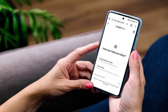 Woman using a mobile phone with ChatGPT on the screen. This app is a chatbot based on Artificial Intelligence developed by OpenAI. 